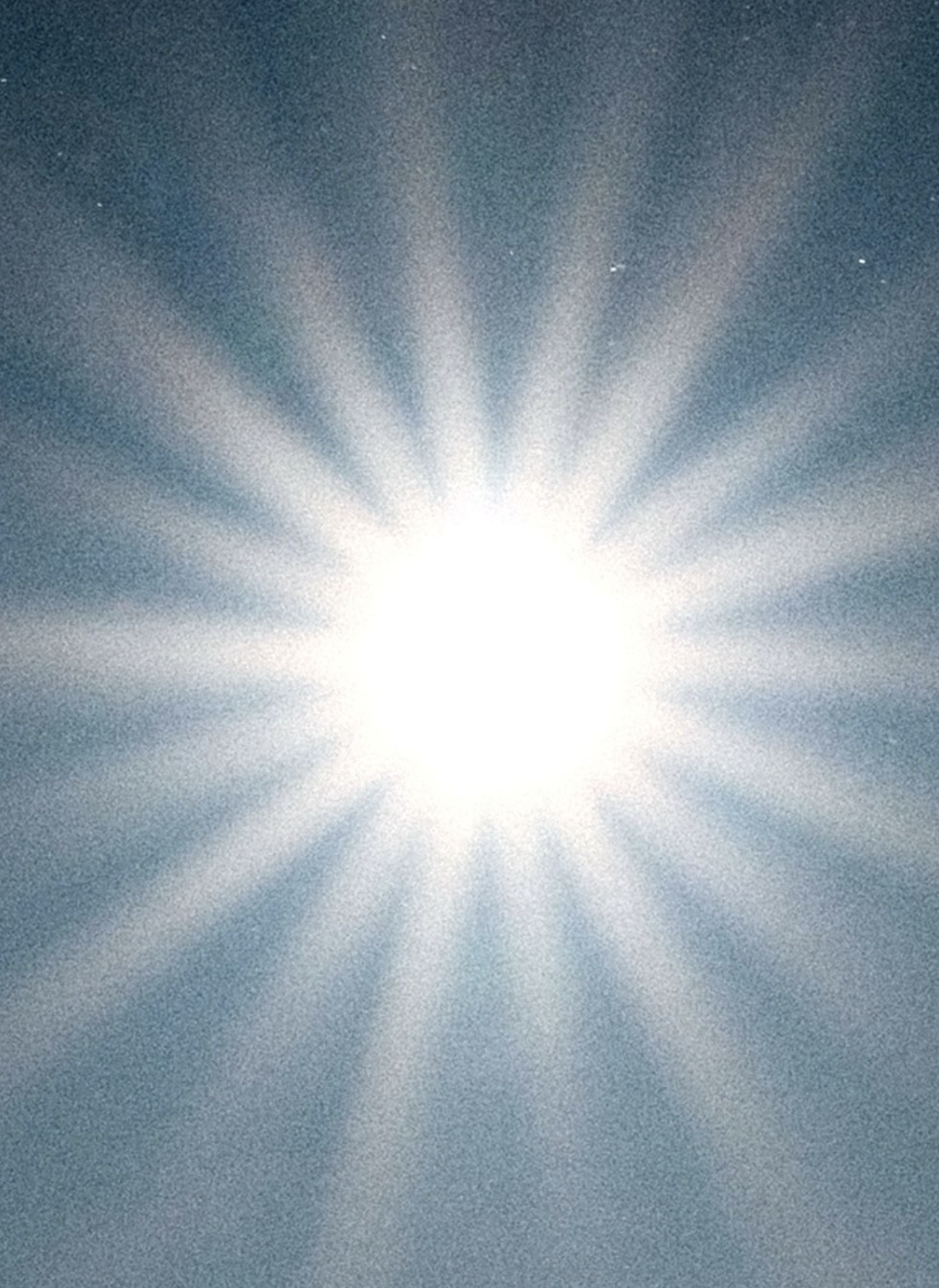 Sunburst through textured blue sky